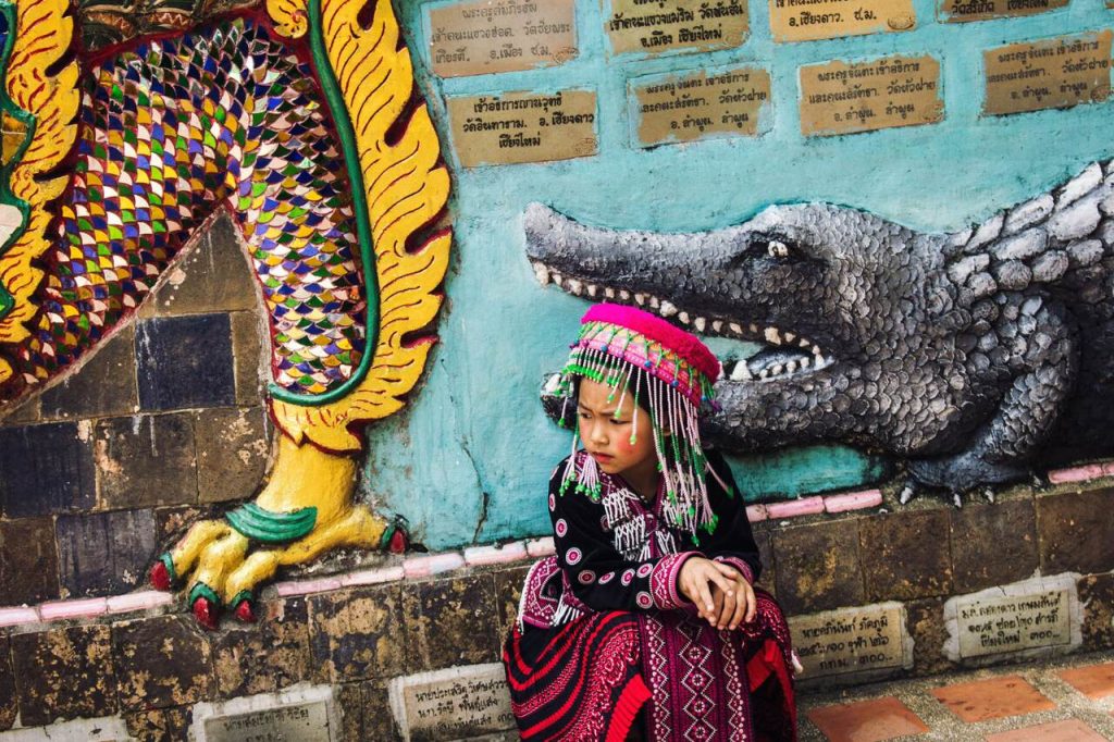 A little tribe girl sitting nxt to a wall at What Doi Suthep in Chiang Mai