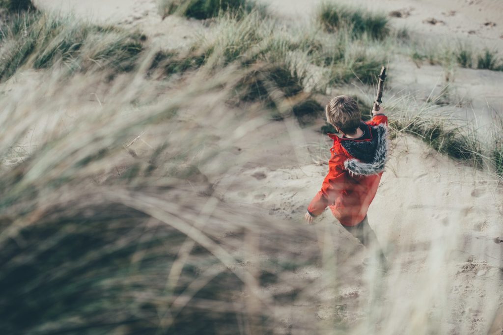 A boy walks through sandy dunes. Hiking with kids