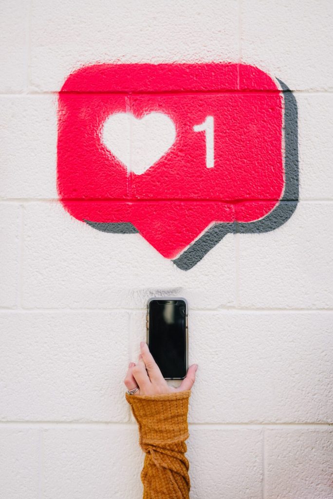 A heart graffiti on a white wall, a smartphone underneath. Lonely abroad