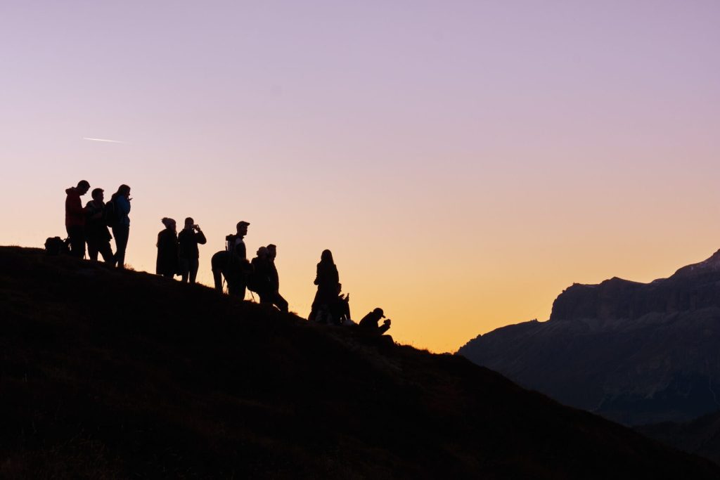 A group of people hiking on a hill at sunset time.