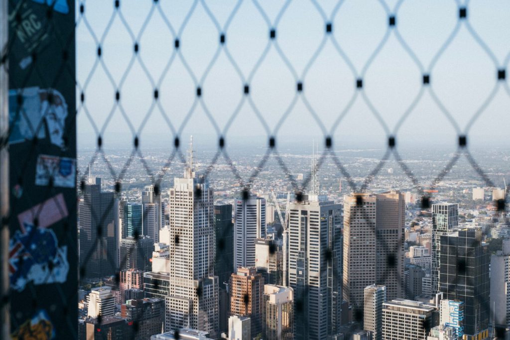 The view of Melbourne from above through a metal fence.