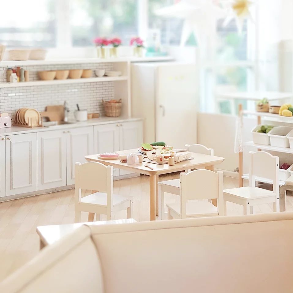 Wooden play kitchen in bright colors with table and chairs.