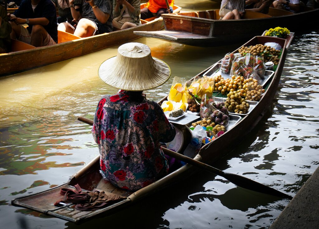 Woman in a small boat full of fruits, best things to do in bangkok with kids