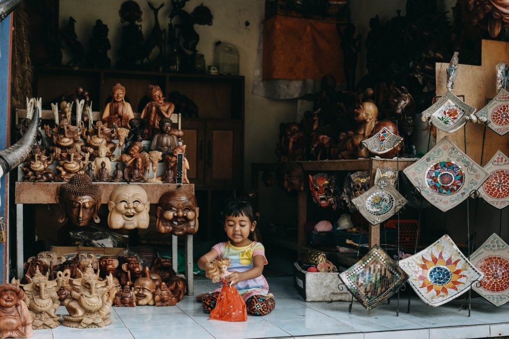 Balinese child playing on the floor with local art pieces.Bali