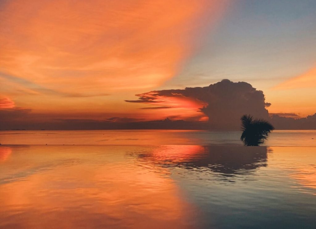 Koh Phangan sunset with the orange sun mirroring in a pool.