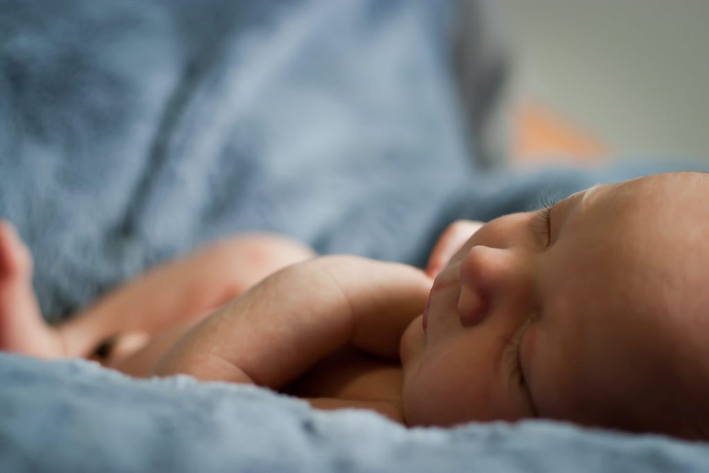 Newborn baby sleeping in a blue blanket. best age to Travel with Kids