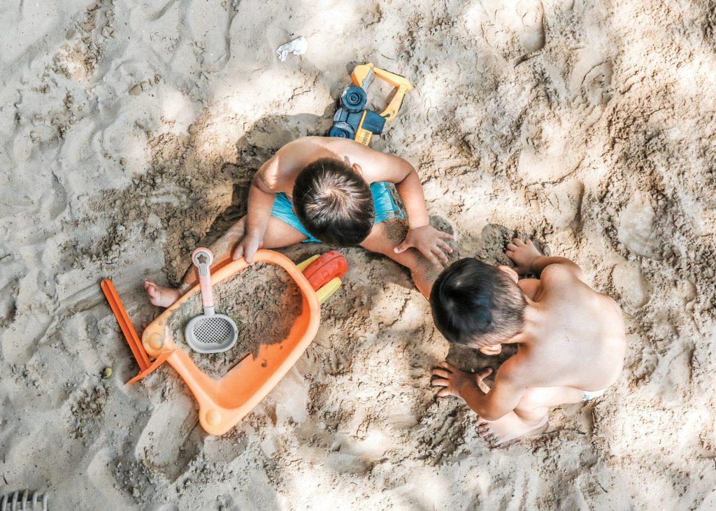 Kids playing at the beach with colorful toys. The best age to travel with kids