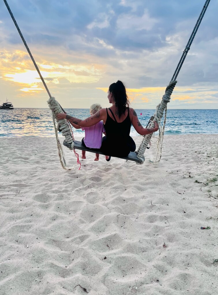 Mum and toddler daughter on a huge beach swing