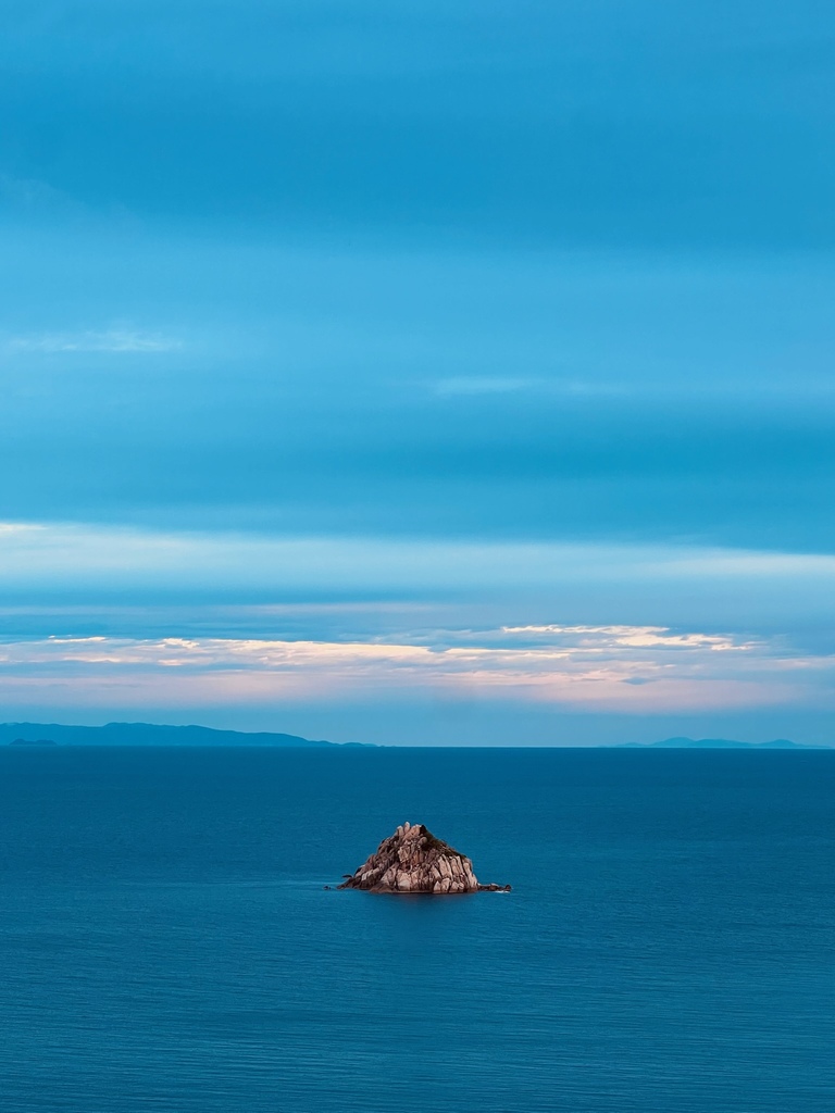 Blue sea with a tiny rocky island