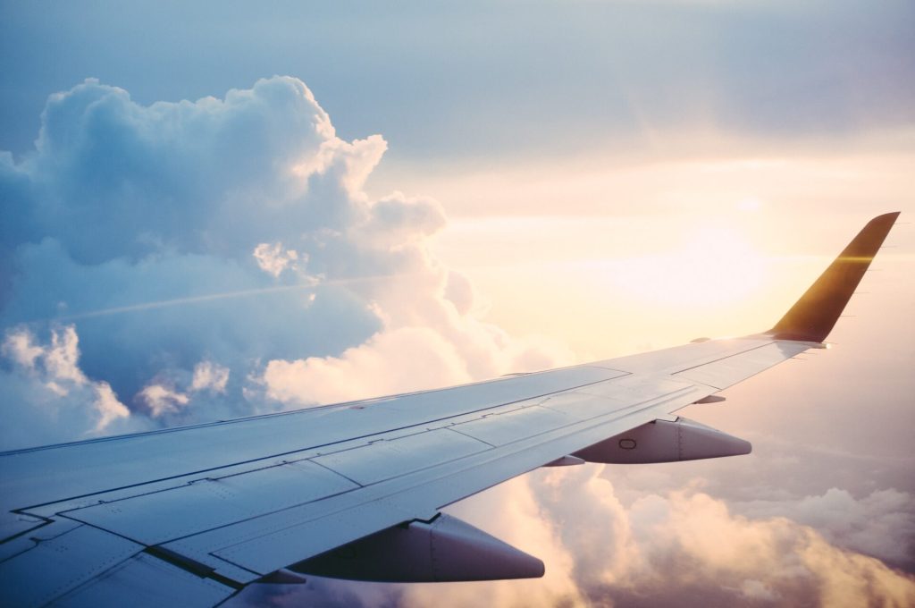 Wing of airplane with white clouds in the background