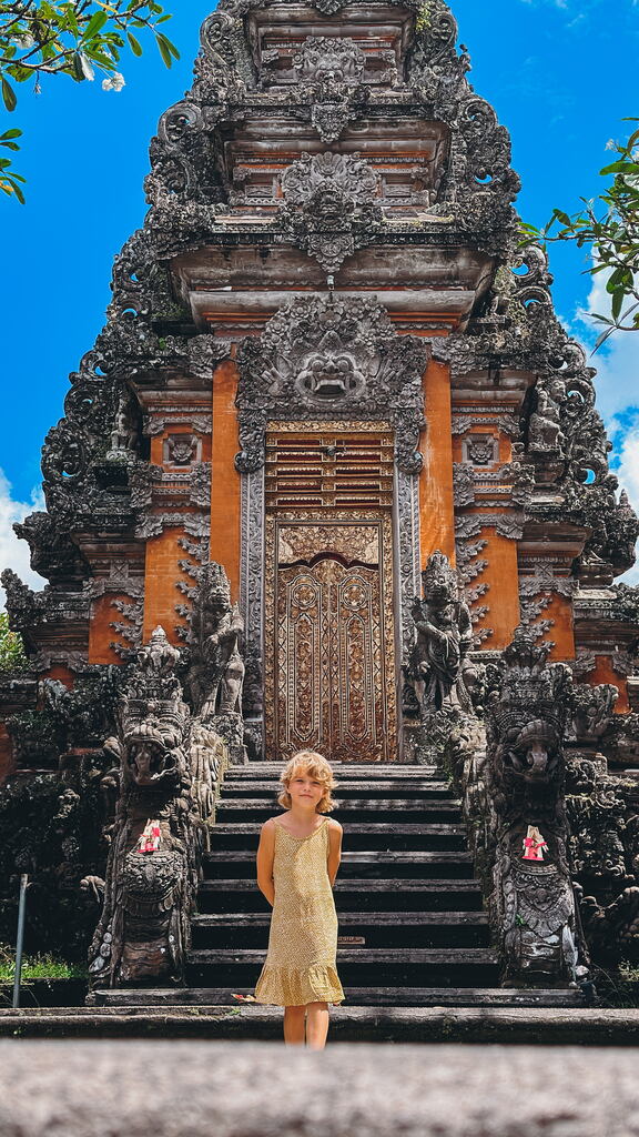 Young girl in yellow dress in front of a balinese temple.