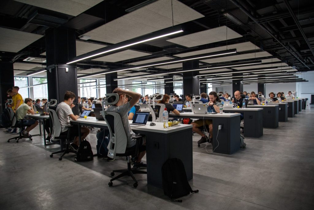 A huge dark office with many employees working on computers.