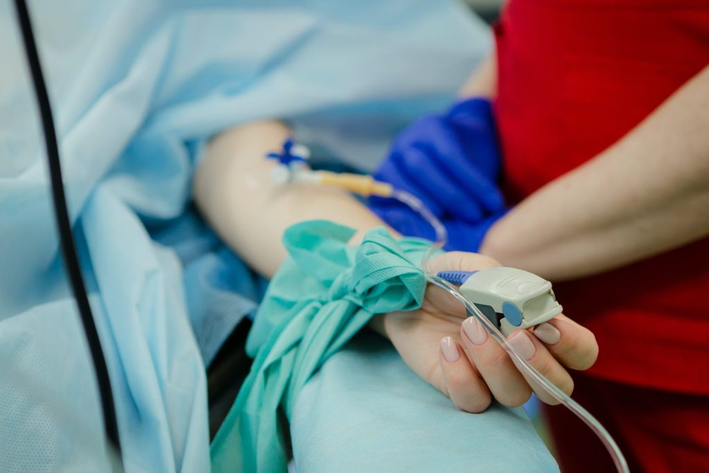 Arm of a women in an ICU. A nurse is standing next to her. Digital Nomad Health Insurance Plan