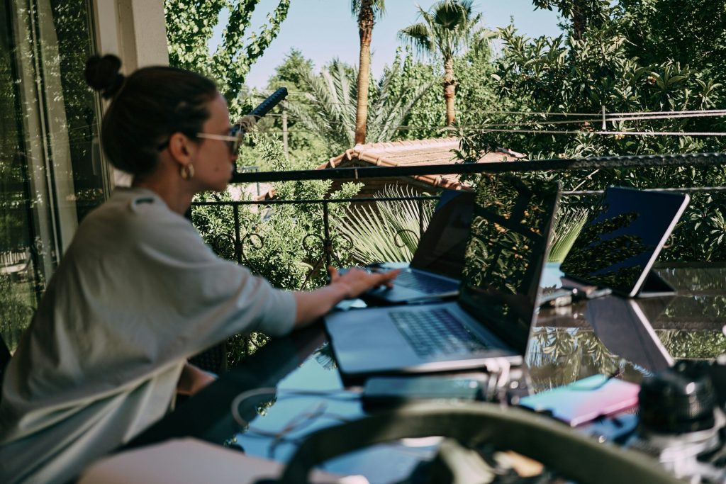 What is a Digital Nomad? Woman working on her laptop, sitting on her balcony.