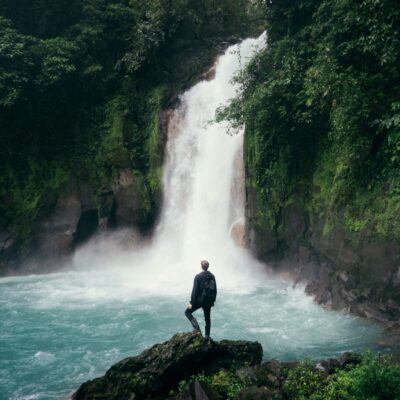 Digital Nomad Man standing in front of a huge waterfall