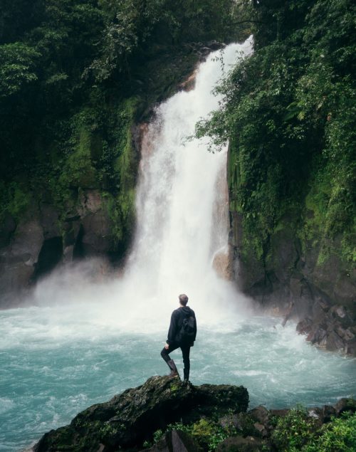 Digital Nomad Man standing in front of a huge waterfall