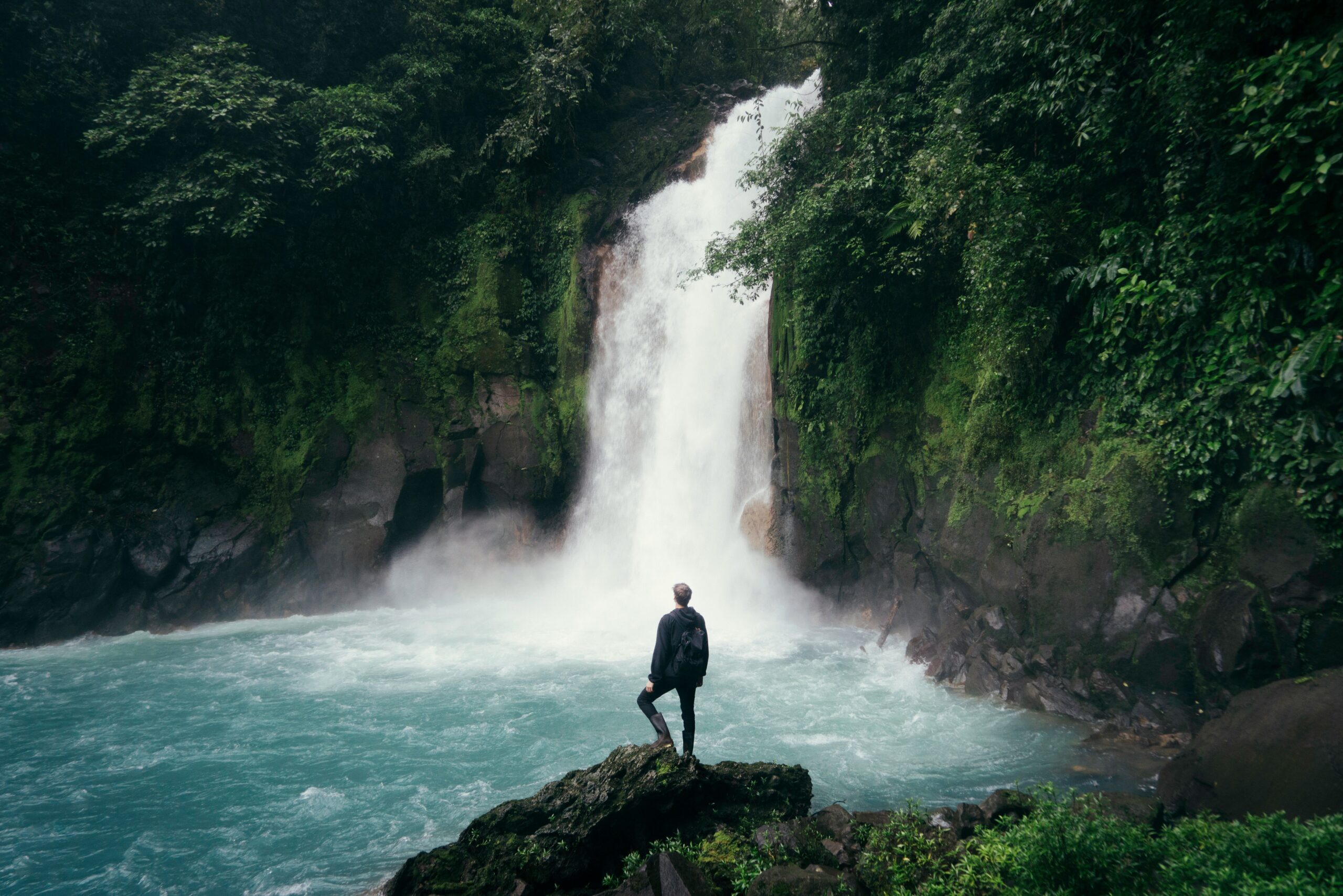 Digital Nomad Man standing in front of a huge waterfall