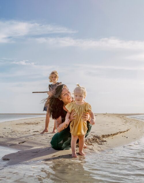 Mum with two young daughters on the beach.