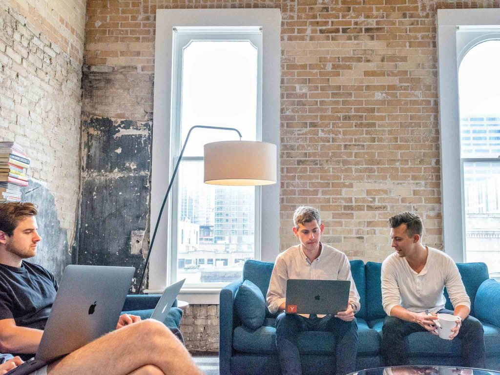 finding house as a Digital Nomad: three male nomads sitting on a couch with laptops on their laps