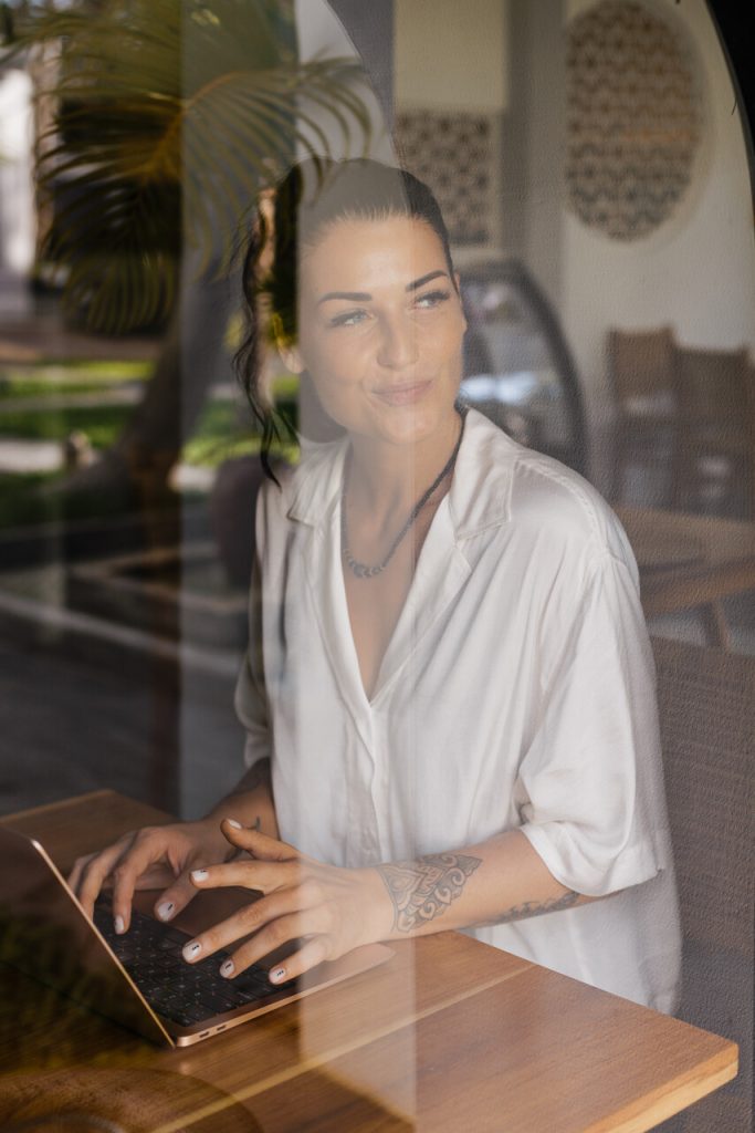 Lulu Lundt working on her laptop in a wooden cafe, remote work-from-home jobs