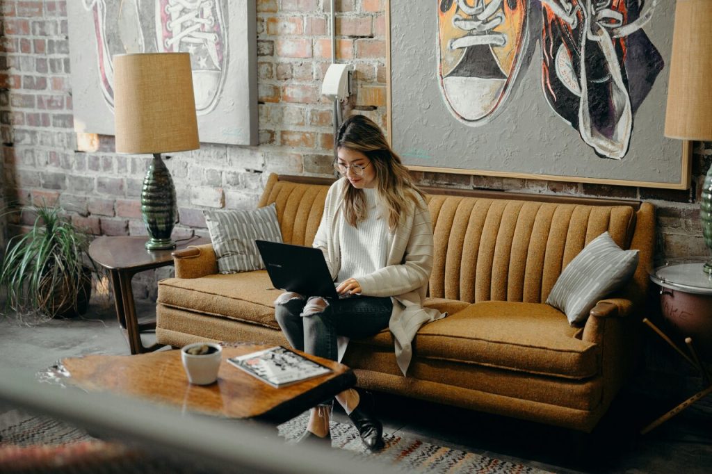 Woman sitting on a yellow couch, working on her laptop