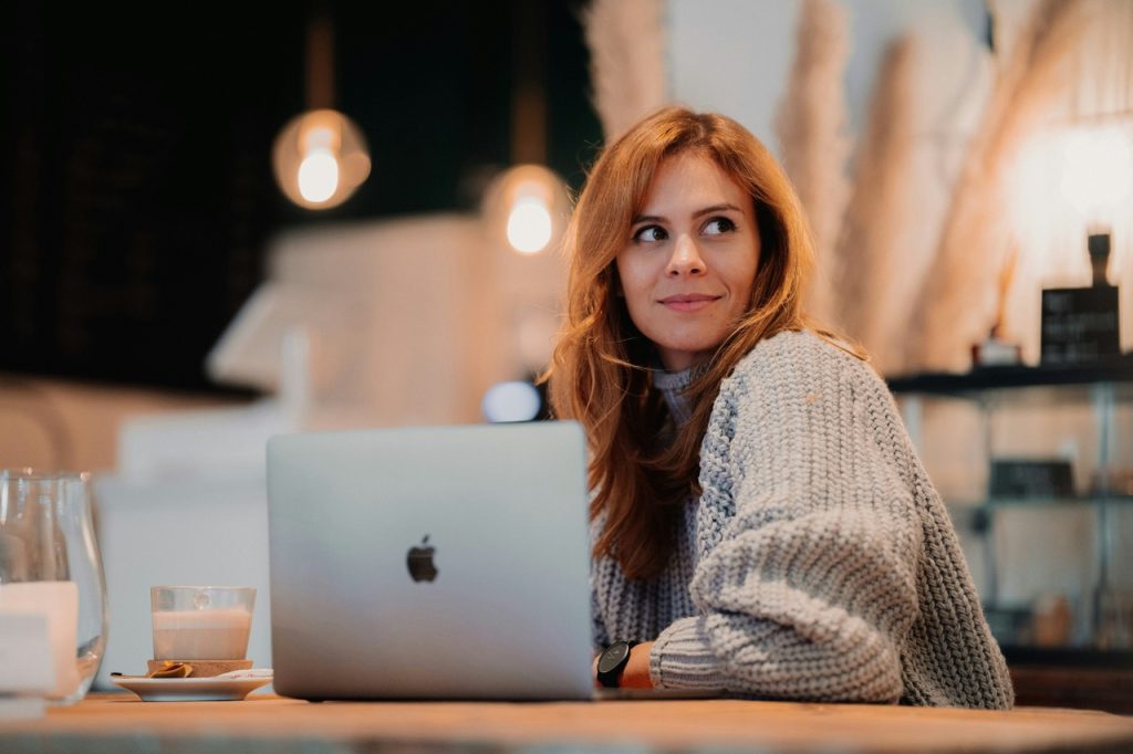 Redhead woman sitting on the laptop, looking to her left, remote work