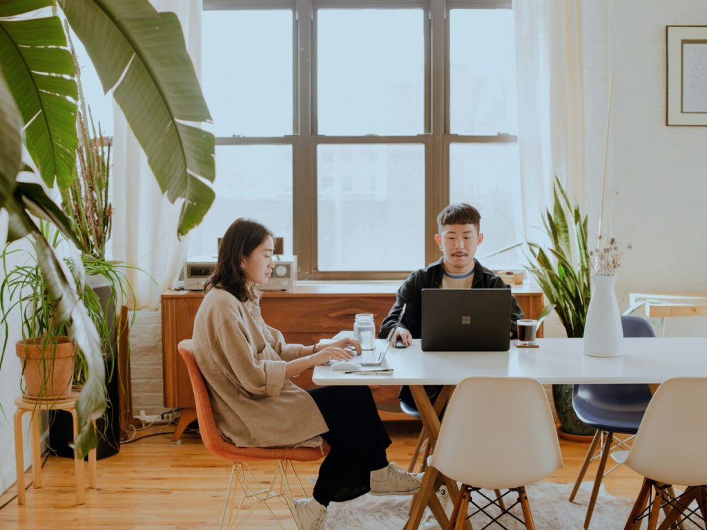 Two remote workers sitting on the table and working together on their laptops