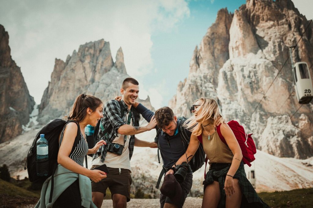 four young hikers laughing in front of mountains