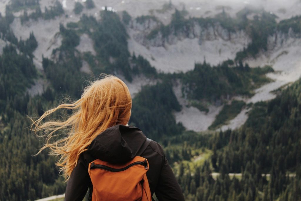 Woman from behind standing in front of a huge mountain. Digital Nomad Taxes