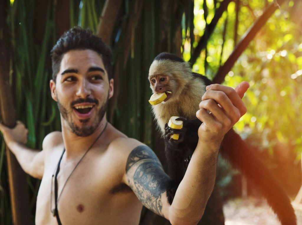 Young male tourist holding a monkey on his arm