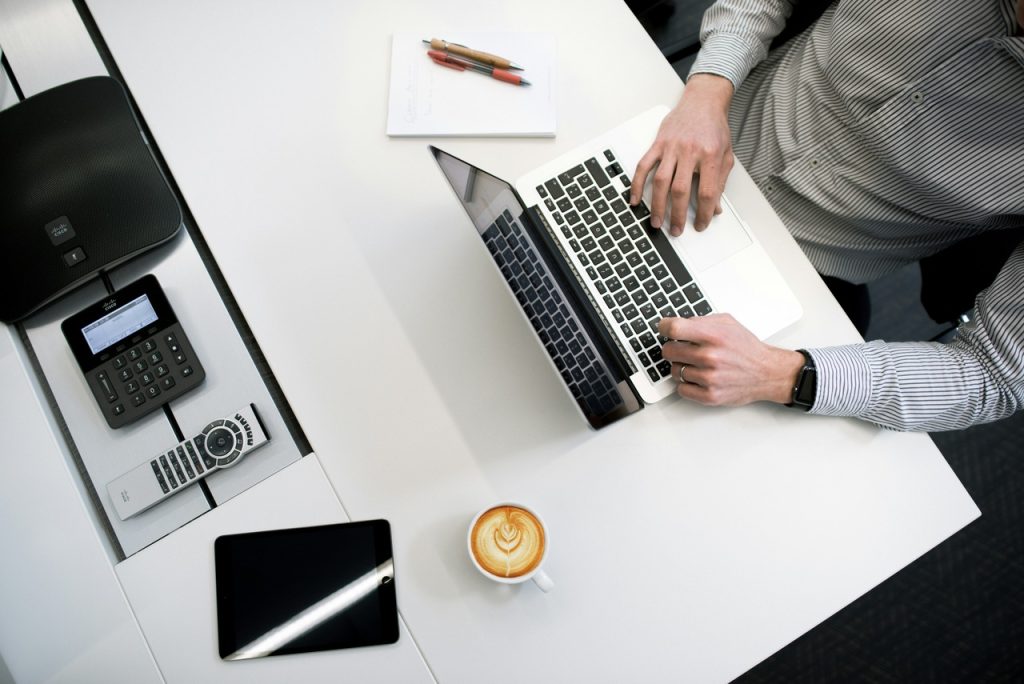 Man sitting on a desk working on his laptop