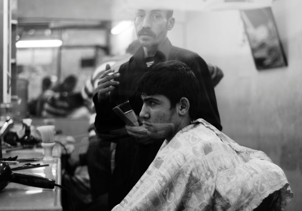 young client sitting in front of an older barber