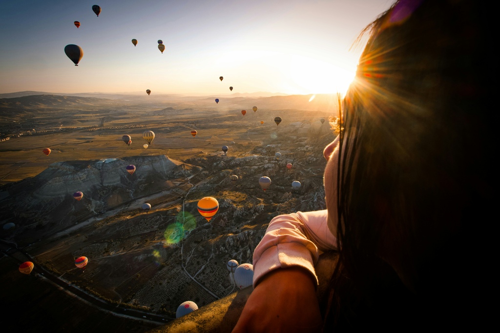 Woman watching hot air balloons at sunset