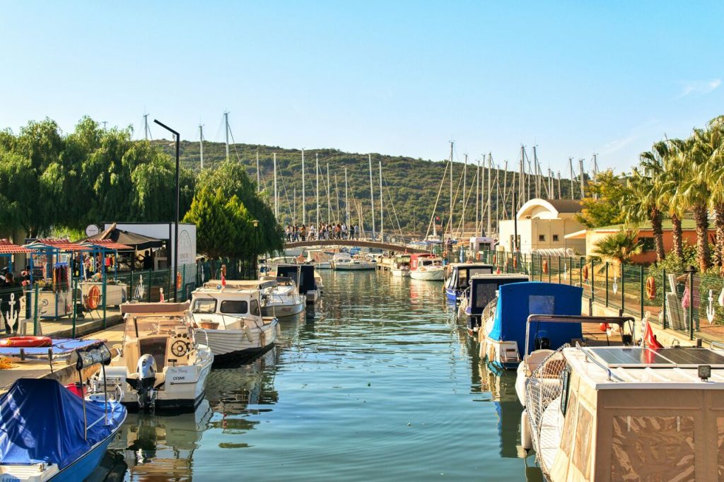 Marina with white boats left and right and a green hill in the background