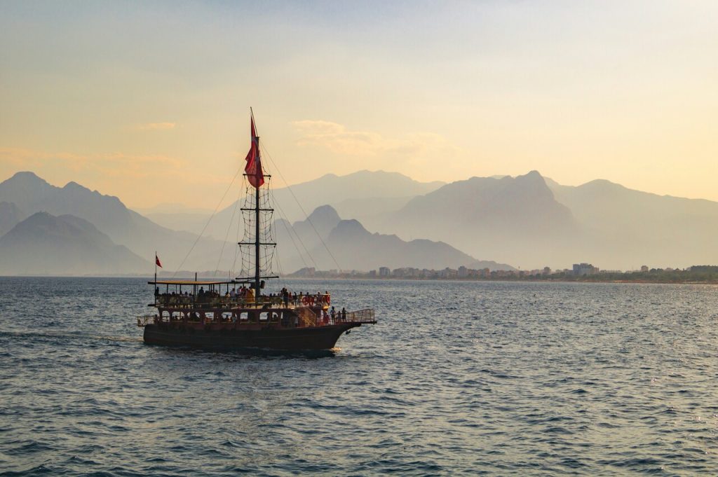 Big wooden sailing boat on the sea, hills in the background