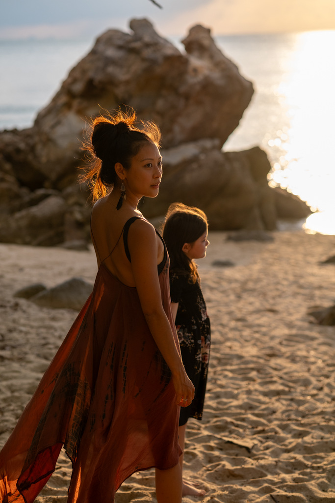 mother and daughter walking on the beach, holding hands, sunset time, traveling as a single parent