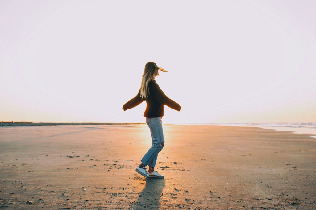 woman freely turning around on a beach