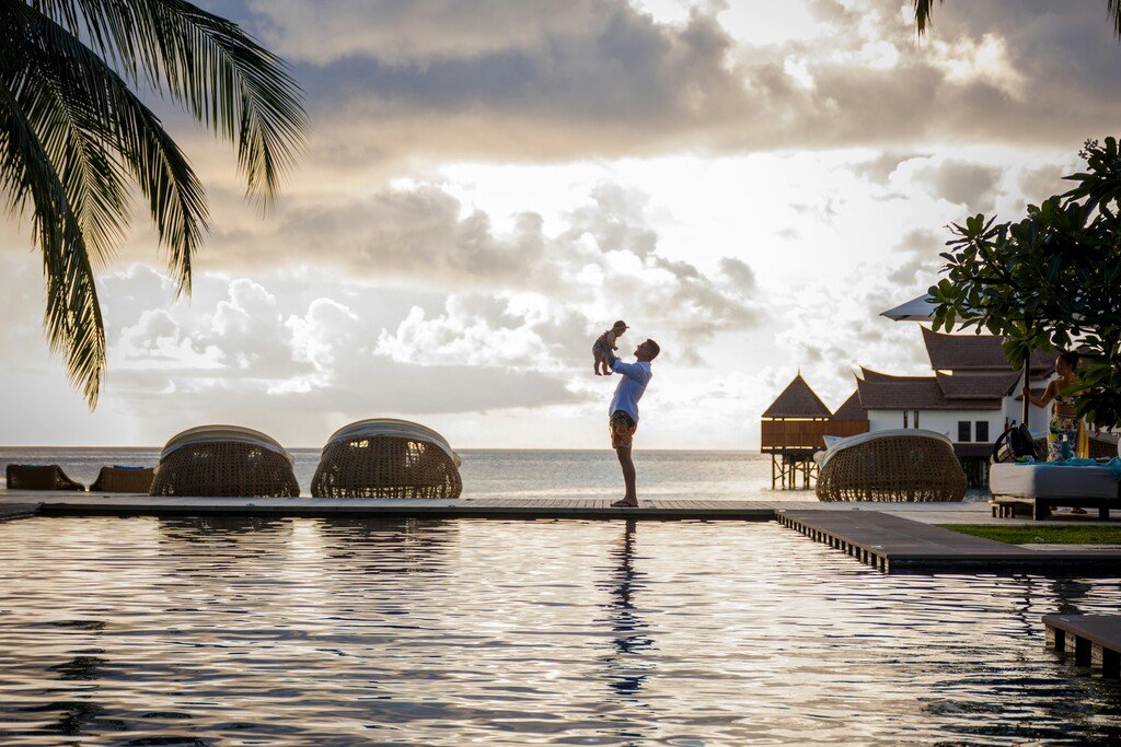 dad holds his toddler in the arms, standing at a pool, full time traveling families