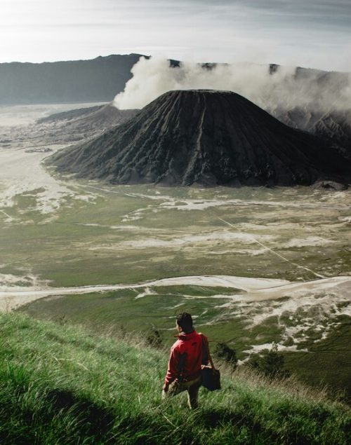 Hiking man, volcano in the background, How to travel around the world and make money