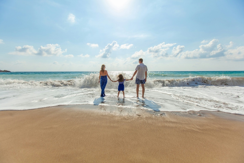 family with toddler walking into the water on a beautiful beach