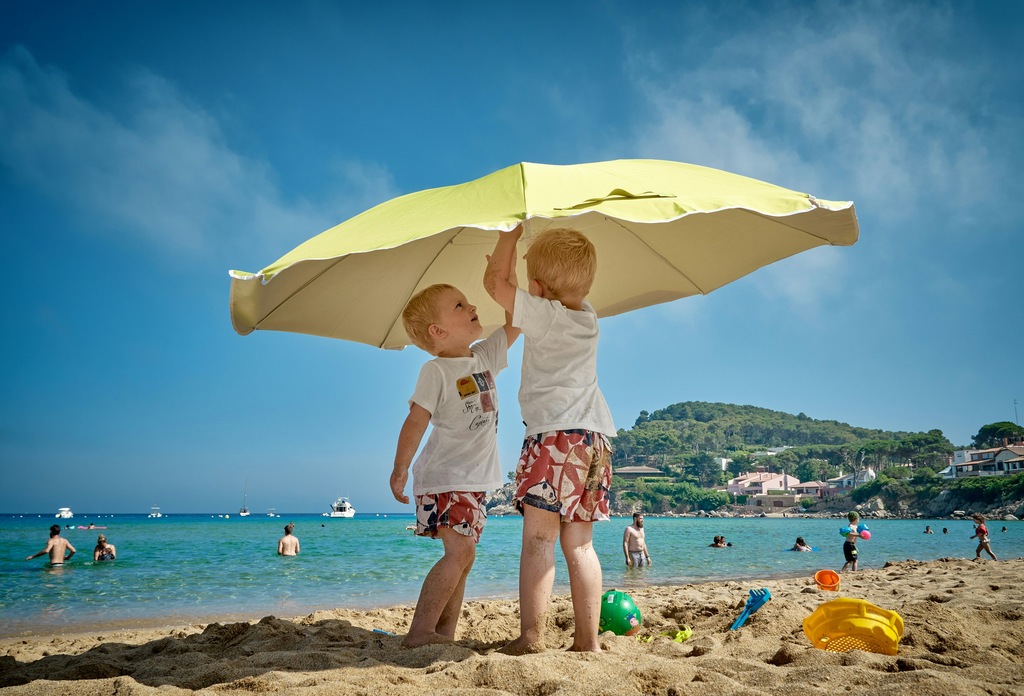 two small boys on the beach with a sun umbrella, digital nomad packing list, nomad essentials