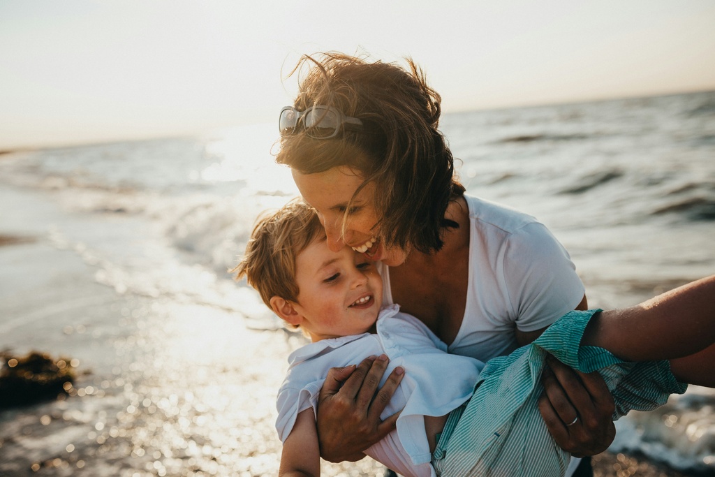 woman on the beach holding her toddler boy in the arms