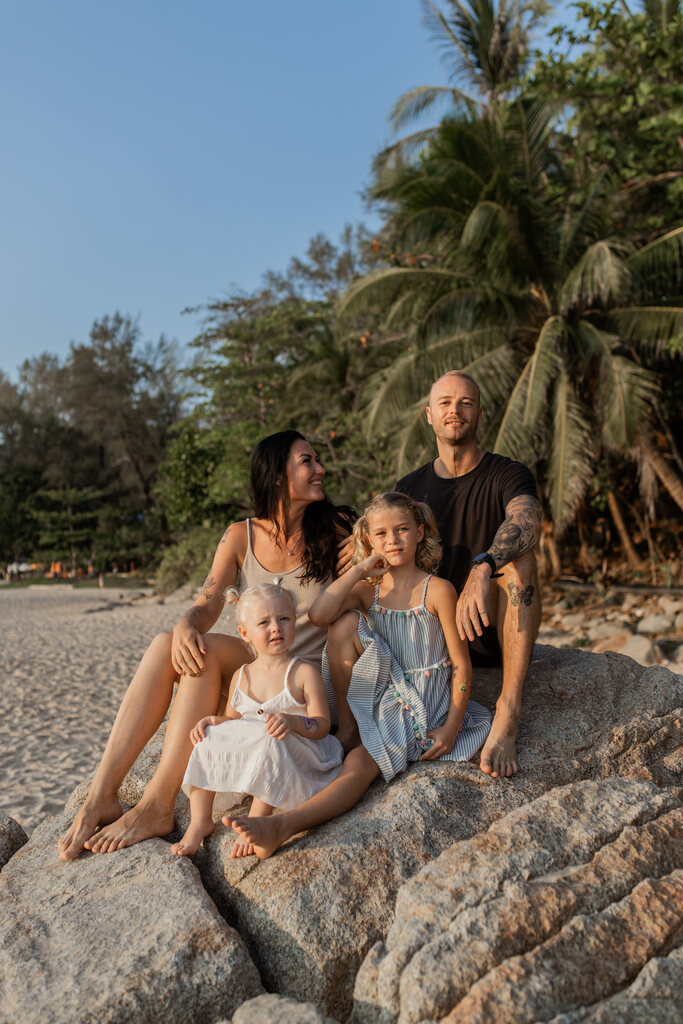 Family of four sitting on a rock on the beach