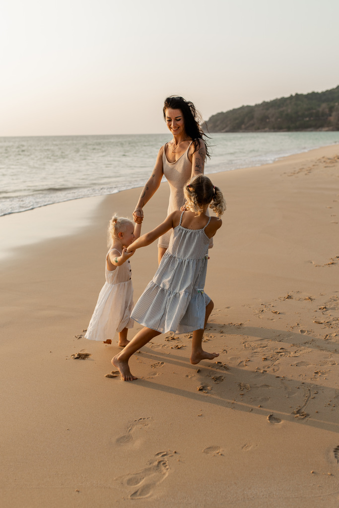 mom playing on the beach with two small daughters