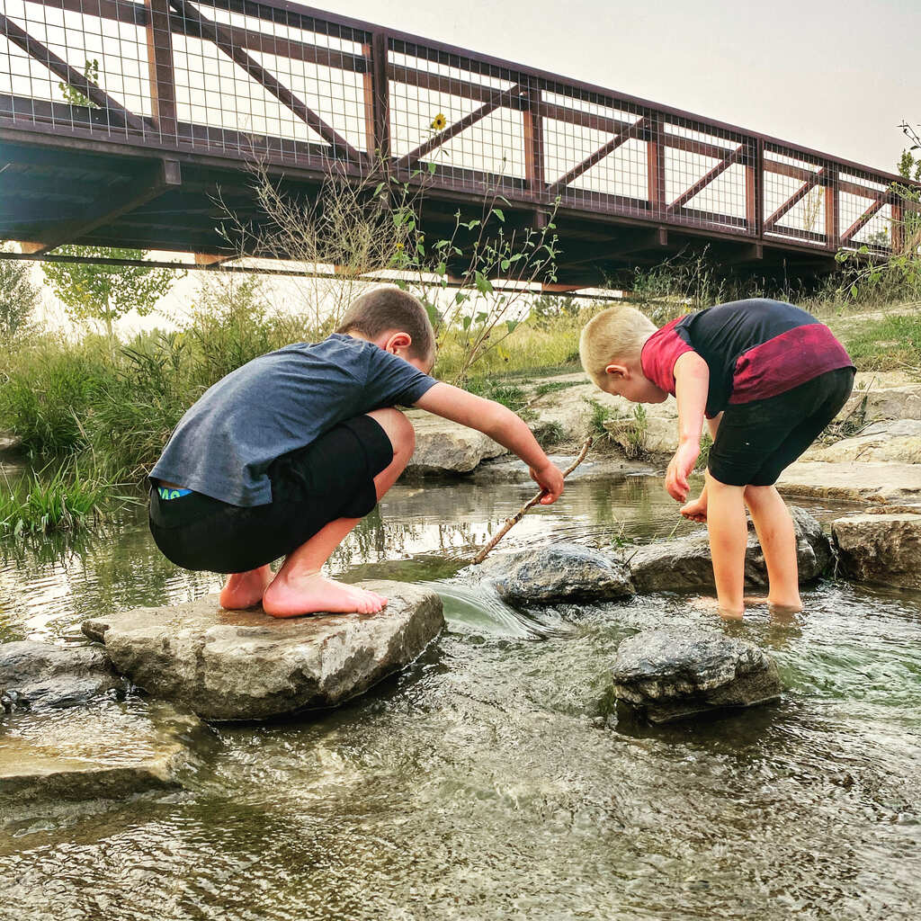 Two young boys playing in a water stream