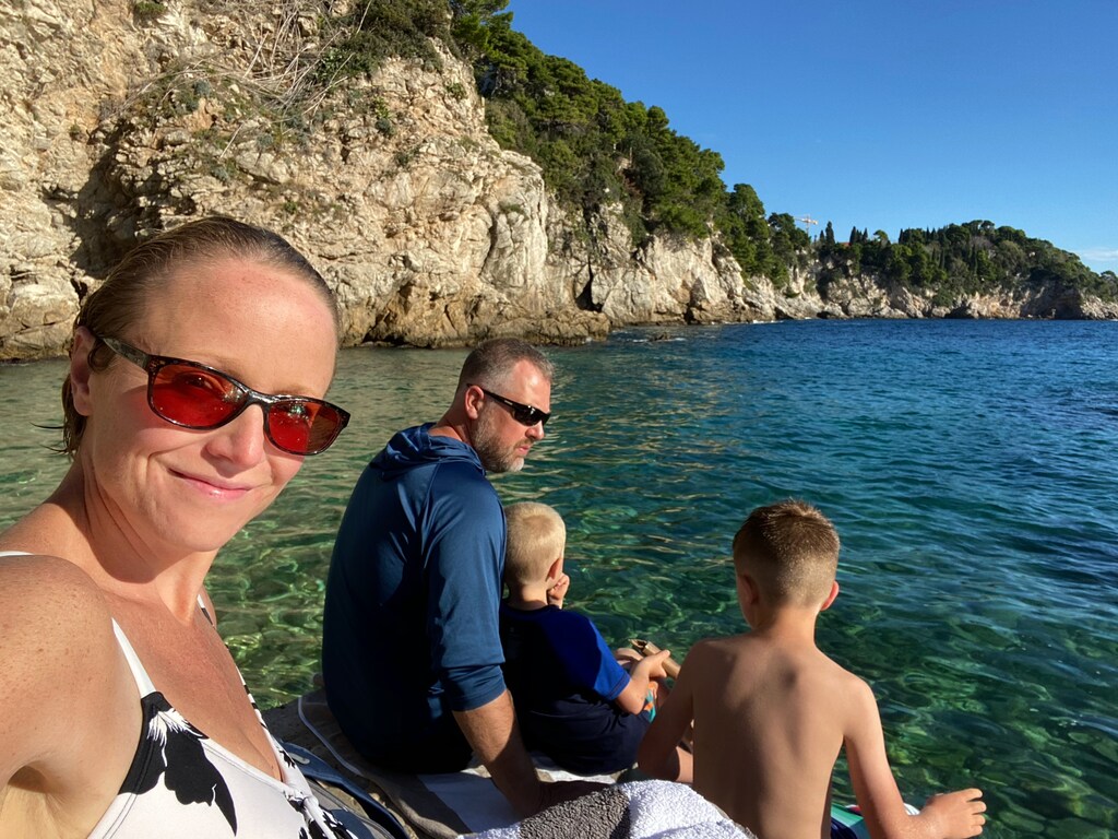 Family of four in a boat on clear waters, worldschooling tweens