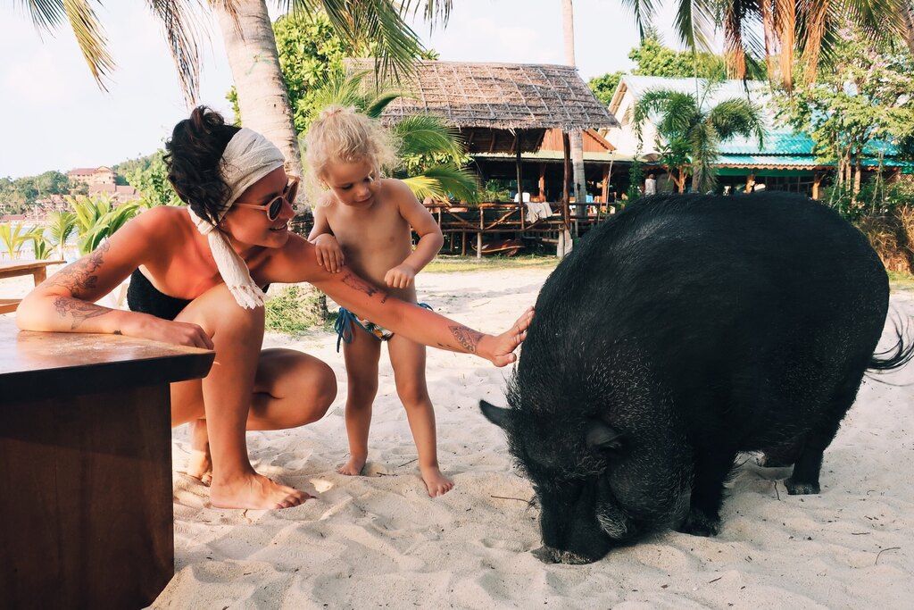 Mum and daughter petting a beach pig