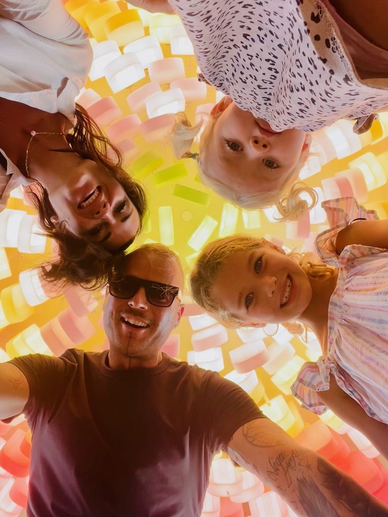 Family of four looking down into the camera that lays on the floor, full-time family travel