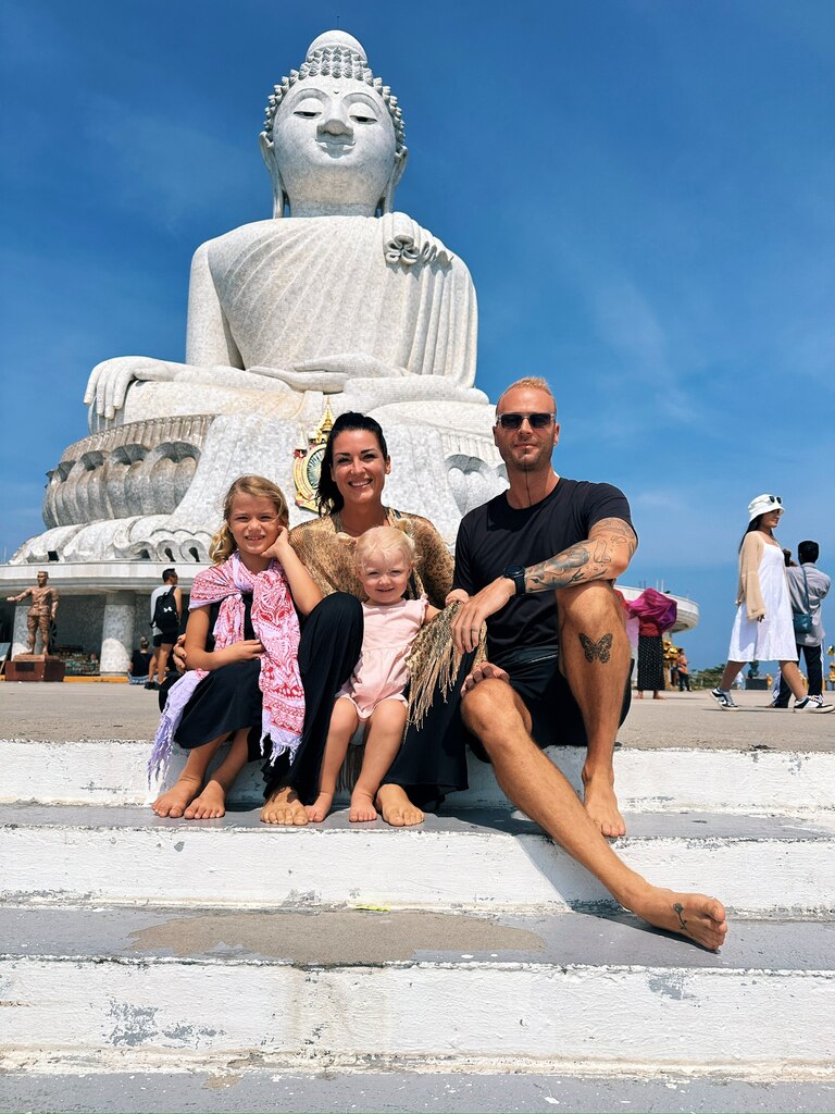 Family of four sitting in front of Big white Buddah statue in Phuket