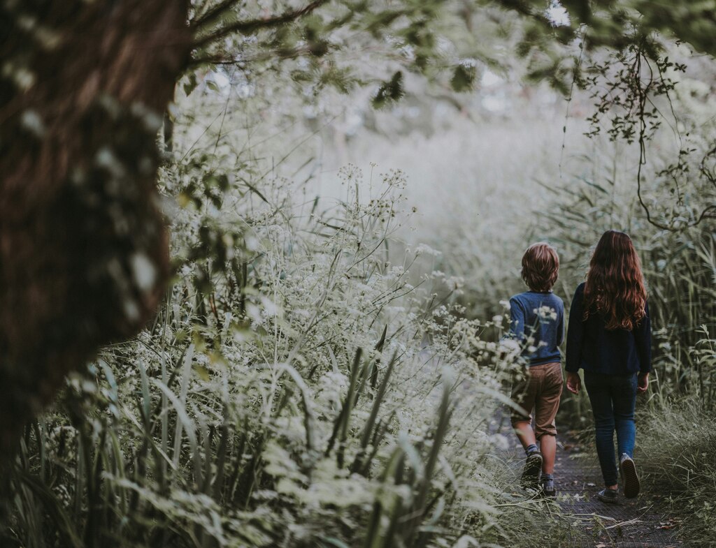 Two kids walking through lush green gras